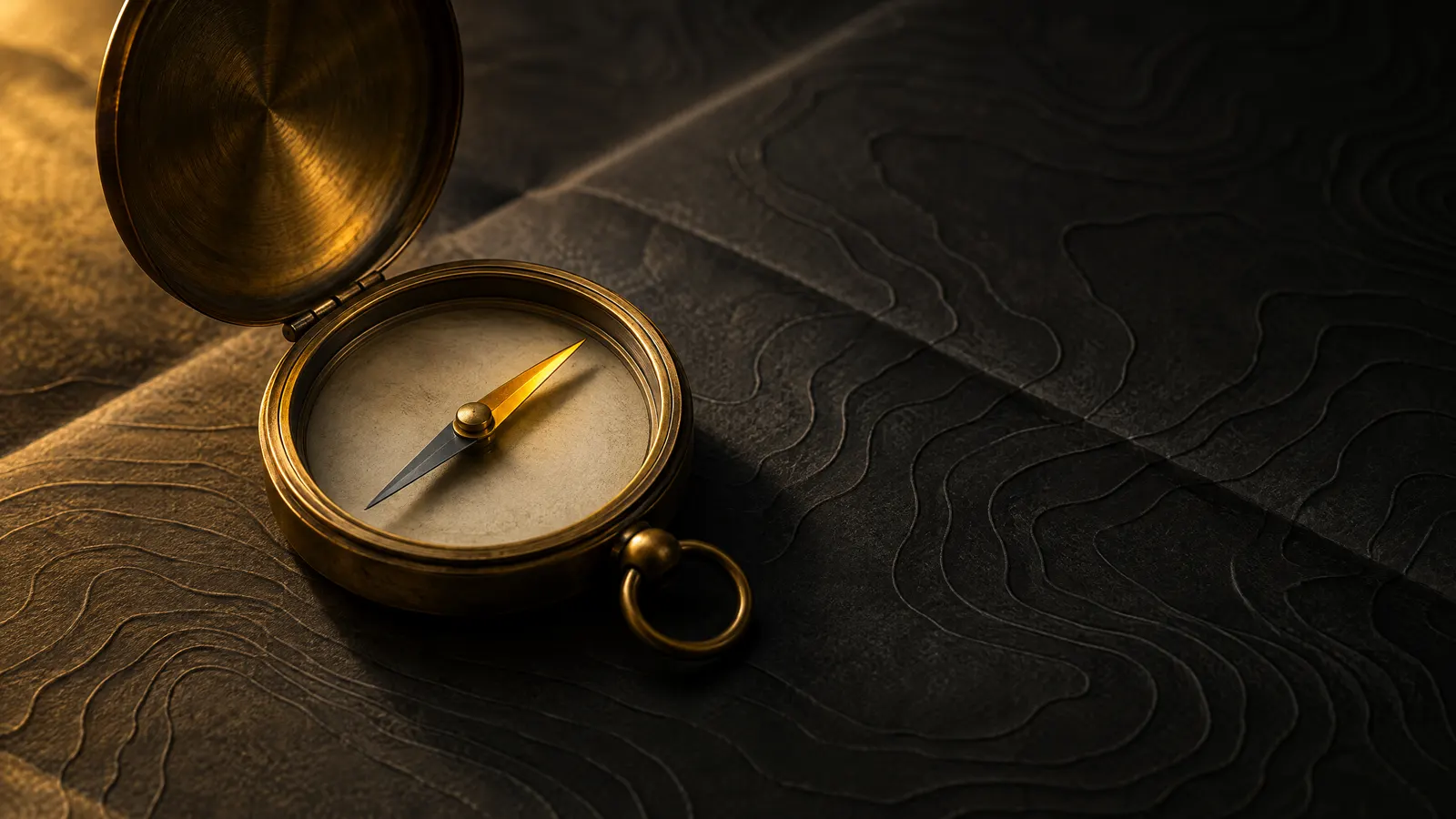 An open brass pocket compass resting on dark paper embossed with contour lines, lit by warm amber light.